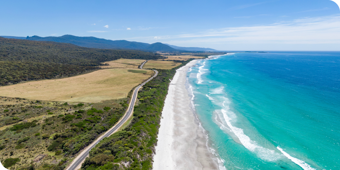 Stunning high angle aerial panoramic drone view of Denison Beach and the A3 Tasman Highway just north of the village of Bicheno on the east coast of Tasmania, Australia on a sunny day.